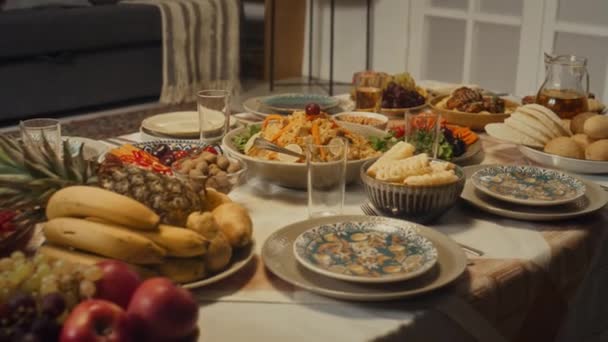 伝統的な料理 フルーツ 塗装された倉庫が付いている洗練されたお祝いのディナーテーブルの人々の側面の映像は すべて家族と一緒に家でイスラムのウラッツァーナのお祝いに優雅に飾られていません — ストック動画