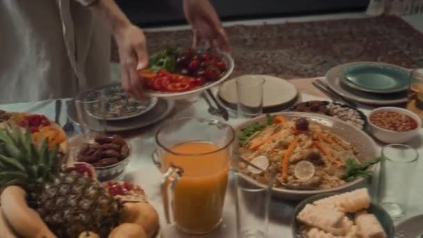 家族と一緒に家でEid FitrまたはLesser Eidを祝う前に伝統的な食事とテーブルを祝うために果物や野菜を提供する認識できないイスラム教徒の高角度映像 — ストック動画