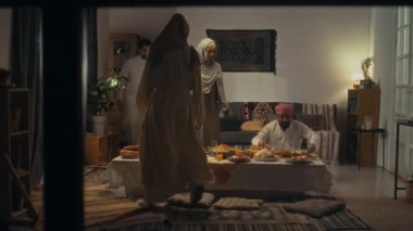 Evde Uraza Bayram 'da aile şenliği sırasında tabakları ve tabakları değiştiren iki müslüman kadının kamera görüntülerini geniş açıdan izleyin.