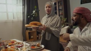 Yeni pişmiş pide ekmeğiyle gelen tesettürlü genç bir kadının bayram yemeğinde kocasına ve akrabalarına sunduğu yan görüntüler.