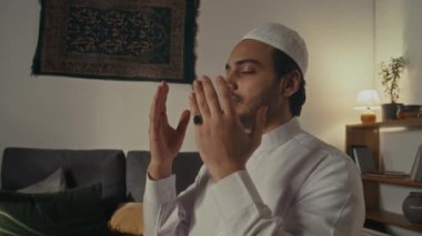 Arap sakallı Müslüman 'ın evde Allah' a dua edişini çekerken yüzünü ve vücudunu gösterip ayağa kalktığını gösteren bir sahne.