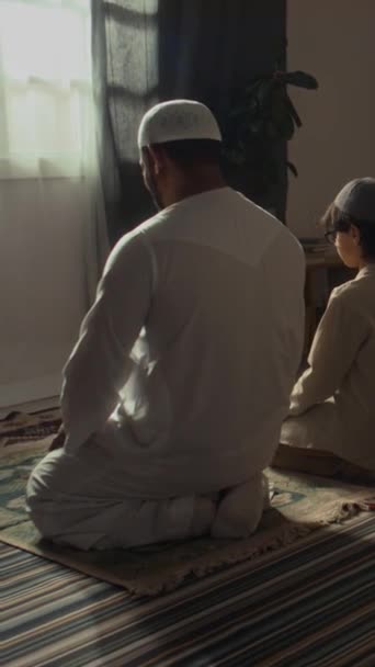 身份不明的父亲和儿子跪在地板上 在家里表演纳马兹舞的后背垂直镜头 — 图库视频影像