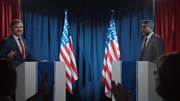印度和高加索男性总统候选人从讲台上向公众挥手致意 然后握手致意 然后开始辩论的中等镜头 — 图库视频影像