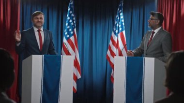 Tartışmaları bitiren, birbirlerine teşekkür eden, el sıkışan, seyirci ayakta alkışlayan ve fotoğraf çeken beyaz ve Hint asıllı Amerikan başkan adaylarının tam karesi.