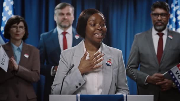 アフリカ系アメリカ人の若い女性政治家が トリビューンで有権者に演説し スピーチを終わらせ 感謝し 振る舞うアメリカ合衆国共和党の大統領または知事の指名をキャンペーンを展開する中型ショット — ストック動画