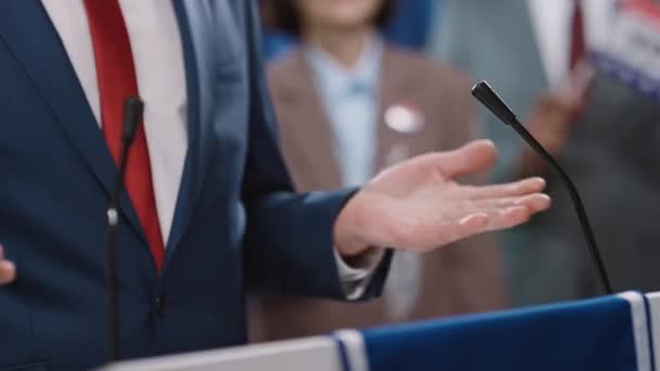 青いスーツ 白いシャツ 赤いネクタイで匿名の男性コーカサス候補者の手と真ん中のショット 選挙大会での彼の税務課題を説明しながら — ストック動画