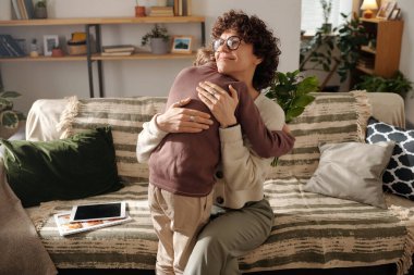 Sevecen bir çocuğu kucaklayan mutlu genç bir kadın. Bahar tatilinde onu tebrik ediyor ve ona bir demet taze çiçek veriyor.