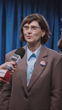 Elinde mikrofon ve kamerayla gazetecilerin röportaj yaparken orta yaşlı Kafkasyalı kadın Senato adayına sosyal ve sağlık politikaları hakkında sorular sorarken orta boy dikey görüntüsü