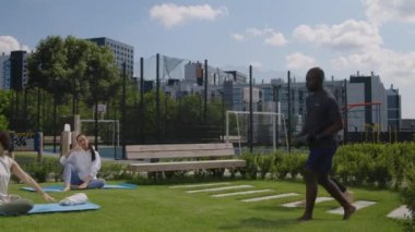 Yoga antrenmanına başlamadan önce ortak çatı parkına spor paspaslarıyla gelen ve neşeli kadınlara katılan komşuların tam görüntülerini.