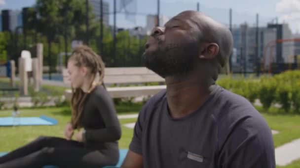 アフリカ系アメリカ人の若い男が公園で屋外トレーニングをしながら首を温めている映像をサイドチェスト — ストック動画