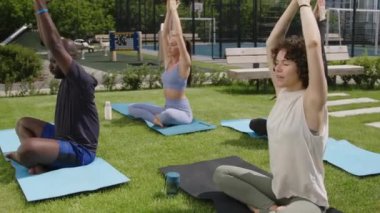 Kafkas Yogası yapan kadın öğrencilerin videolarının tamamı Asana tekrarlayan ve apartman parkında otururken namaste işareti yapan çeşitli öğrenci grupları için yoga yapıyor.