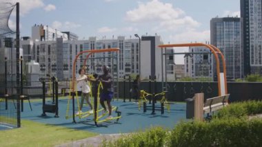 Çeşit çeşit apartman dairesi komşularının güneşli bir günde çatıdaki spor salonunda spor yaparken çekilmiş geniş görüntüler.