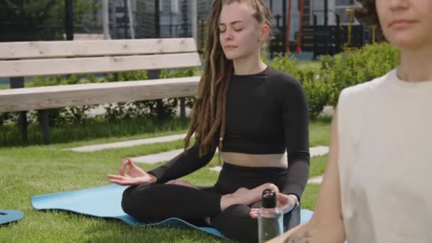 若い白人女性の側面映像 ドレッドロック 屋根のコンドミニアムパークでジャイアン泥をやっている蓮の位置で瞑想 — ストック動画