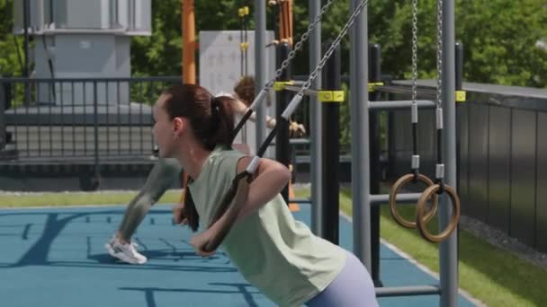 Vedlejší Záběry Pozitivní Běloška Culíkem Dělá Kliky Pomocí Gymnastických Kroužků — Stock video
