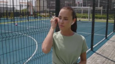 Beyaz saçlı, at kuyruklu çekici bir kadının kulaklık takıp, akıllı sepetle müzik çaldığı ve çatıdaki spor sahalarında antrenman yapmak için uzaklaştığı orta boy görüntüler.