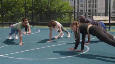 Çeşitli sporcuların kardiyo yaptığı yan görüntüler. Eğlence sahasında omuz omuza kaldırma pozisyonu.