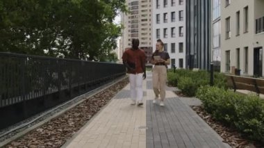 Şehir parkında dizüstü bilgisayar ve tabletle yürüyen çeşitli iş arkadaşlarının tam görüntüleri ve iş sorunlarını çözmek için beyin fırtınası fikirleri.