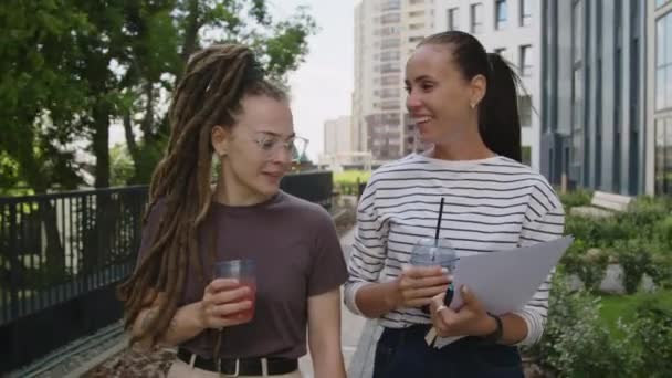 柔らかい飲み物で公園を散策する2人の白人女性のチェストアップ追跡ショットと仕事の進捗と新しいプロジェクトについて話す — ストック動画