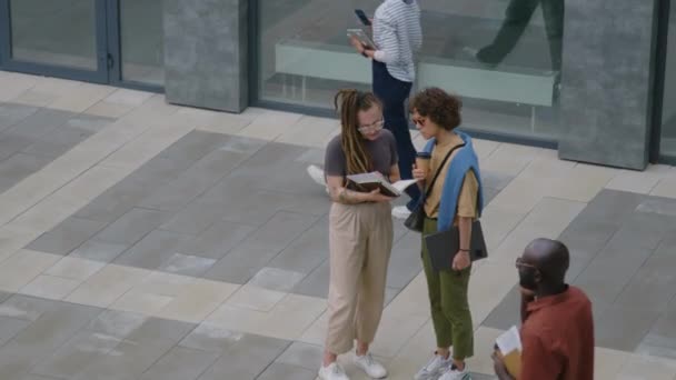 外のオフィスビルに立っている間 昼休みにビジネス文書を議論している2人の白人女性の同僚のオーバーヘッド映像 — ストック動画