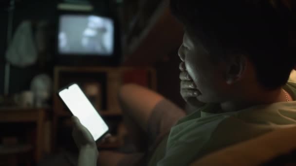 中镜头 疲惫的中国年轻人在下班后呆在家里的时候 用智能手机 打呵欠 然后抱着枕头躺在床上睡觉 — 图库视频影像