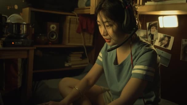 Средние Кадры Молодой Китайской Женщины Наушниках Сидящей Двухъярусной Кровати Микроквартире — стоковое видео