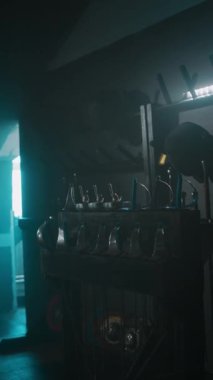 Beyaz kadın folyo eskrimcisinin dikey yan görüntüleri. Koyu renkli dumanlı salonda antrenman yapmak için uzaklaşıyor.