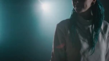 Kafkasyalı kadın eskrimcinin el kamerası görüntüleri. Saçları örgülü, gülümseyen ve erkek partnerle yumruk yumruğa çarpışan. Ya da sisli salonda başarılı bir eğitimden sonra eğitmenle.