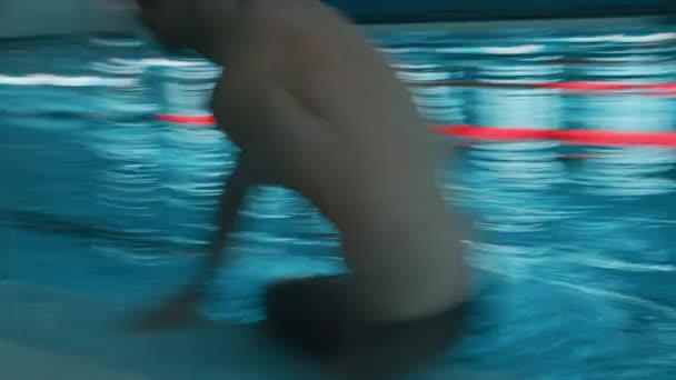 中级射击 缓慢暴露效果 精疲力竭的白人男子游泳运动员穿着黑色泳裤 帽子跃出游泳池 摘下护目镜 呼吸急促 高速赛后休息 — 图库视频影像