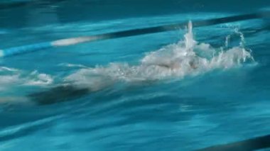 Siyah kauçuk şapkalı genç kaslı beyaz adamın yavaş maruz kalma efektiyle orta boy görüntüler, kırmızı şerit ayırıcıları boyunca yüzen gözlük yarışmada sona yaklaşırken finişe yaklaşıyor.