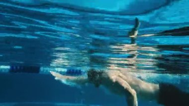 Siyah şortlu, kep ve gözlüklü, tanınmayan erkek sporcu ya da müşterinin havuzda serbest yüzme sahnesinin yavaş çekim görüntüleri.