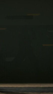 Eskrim pistine gelen, miğfer takan ve yarışmadan önce ya da karanlık salondaki eğitim sırasında folyo kılıcını kaldırırken başlangıç pozisyonu alan erkek folyo eskrimcisinin dikey yan görüntüsü.