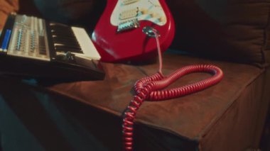 Midi klavye kontrolörünün yanındaki koltukta duran muhteşem kırmızı, beyaz elektro gitar görüntüsü yok.