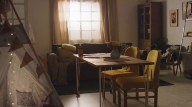 Masasında çiçekler, sarı sandalyeler, duvarlarda resimler ve dekore edilmiş çadır olan modern rahat oturma odasının kamera görüntüleri yok.