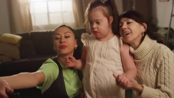 ダウン症の子供とセルフィーを作る女性の3世代の家族のメディア映像と自宅でモバイルカメラのためにポーズ — ストック動画