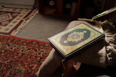 Hiçbir insan, oturma odasında duran altın süslemelerle süslenmiş yeşil sert kapaklı Kuran kitabına yüksek açılı bakmaz.