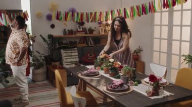 Cinco de Mayo kutlaması için hazırlanan Meksikalı arkadaşlarla dolu. Masaya taze çiçekler koyan iki genç kadın. Erkekler Bunting 'e renkli kurdeleler takıyor.