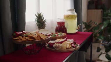 Cinco de Mayo ev partisi için hazırlanmış kırmızı bez, geleneksel Meksika yemekleri ve içecekleri olan orta boy masa fotoğrafları yok. Taco, nachos, salsa, guacamole, salata, ananas ve meyve suyu.