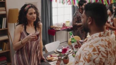 Geleneksel yemek ve atıştırmalıklarla masanın önünde duran, sohbet eden, haberleri tartışan, margarita ve bira içen genç Meksikalı veya İspanyol erkek ve bayan arkadaşlarının orta kavisli pozu.