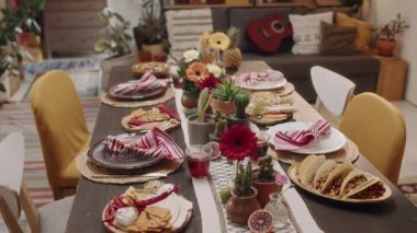 Yakın çekim dinamiği, hiç kimse geleneksel Meksika yemekleri ve abur cuburlarıyla yemek masasında parti için hazır değil - nachos, taco, chalupa, salsa, guacamole, salata, çiçeklerle süslenmiş, kaktüs,