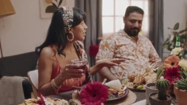 Orta boy, parlak saçlı, bantlı elbisesi olan, elinde kokteyl olan, komik hikâyeler anlatan Meksikalı güzel bir kadının fotoğrafı.