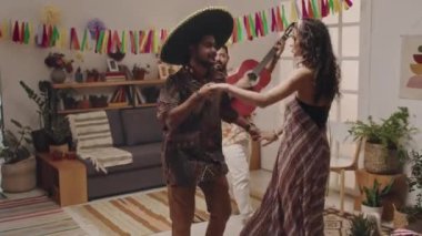 Neşeli Meksikalı bir adamın gitarla müzik çalması, ve şapkalı bir adamın çiçekli güzel bir kızla dans etmesi, Cinco de Mayo 'nun ev partisinde eğlenmesi.