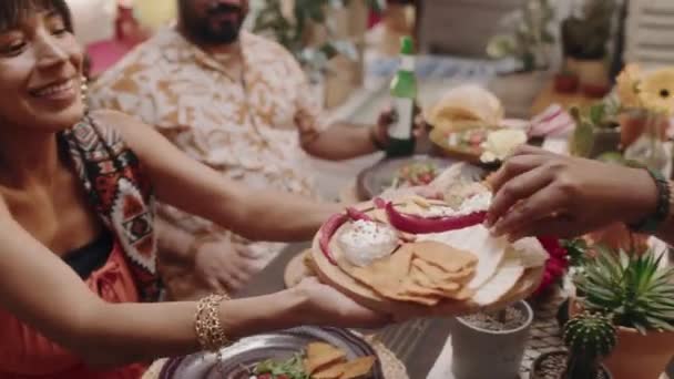 お祝いのテーブルの周りに座っている2人の若いメキシコ人またはヒスパニックのカップルのメディア映像 伝統的な食品を共有し 通過しながら シンコ メイヨー — ストック動画