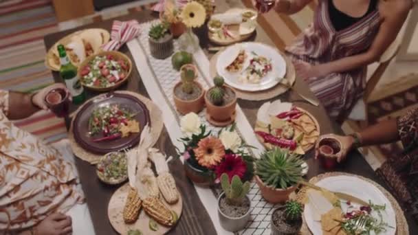 中端是装饰精美的节日餐桌 上面有鲜花 仙人掌和墨西哥传统食品 还有四个年轻人在庆祝节日的同时举杯庆祝节日 — 图库视频影像