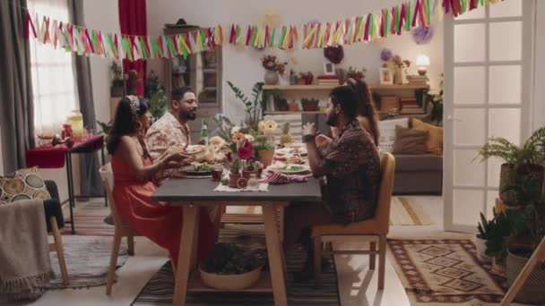 お祝いのテーブルの周りに座っている2人の若いメキシコのカップルの広い映像は 美しく装飾された家でシンコ メイヨーを祝いながら 豪華なディナー チャット シェアを楽しみます — ストック動画