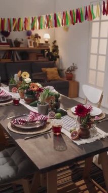 Meksika aile evinde, Cinco de Mayo partisi davetlileri gelmeden önce çelenk, çiçek, kaktüs, tabak, sandalye ve çatal bıçakla süslenmiş yemek masasından çekilen kimse yok.