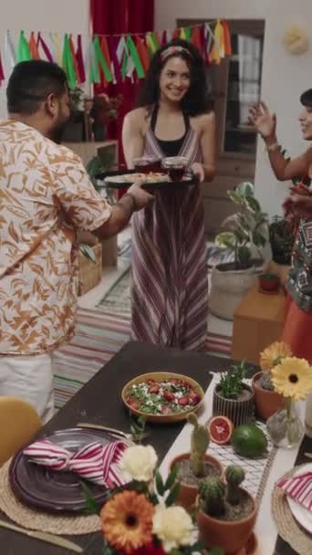 满满一帧快乐的墨西哥年轻女子带着一大盘玛格丽塔鸡尾酒和零食走进客厅 送给朋友们 朋友们欢呼着举杯庆祝 — 图库视频影像