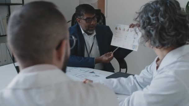 Asyalı Erkek Hastane Yöneticisinin Tıbbi Direktör Baş Cerrahla Ofiste Otururken — Stok video