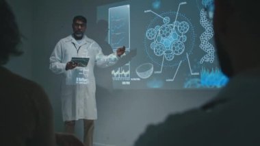 Toplantıda projeksiyon ekranının yanında duran tablet bilgisayarlı orta yaşlı Asyalı erkek klinisyenlerin yeni bağışıklık sistemi ilacı hakkında rapor verirken, meslektaşlarına teoriyi açıklarken tam görüntüler.