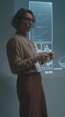 Kafkas kadın bilim adamı ya da profesörün üniversitede ya da konferansta biyokimya dersi verirken, sorular sorarken ve seyircilerle iletişim kurarken orta boy dikey çekim.