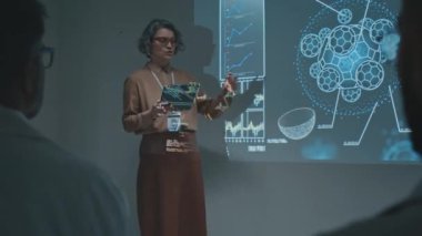 Tıp konferansında doktorlara yeni ilaç veya terapi tanıtan tablet bilgisayarlı Kafkas kadın ilaç satış temsilcisinin tam görüntüsü.